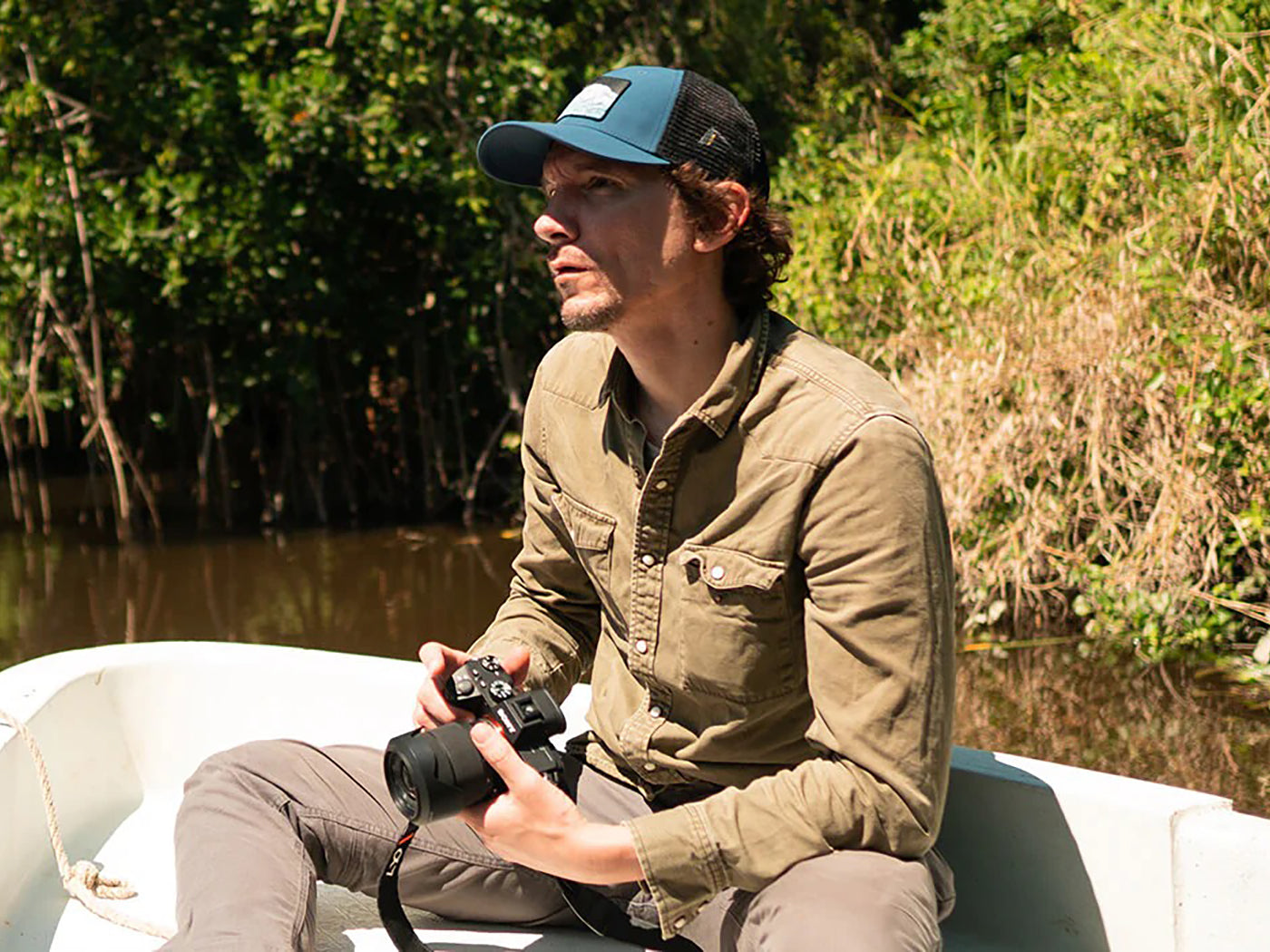 man in the Pantanos de Centla swamp sitting on a boat with a camera