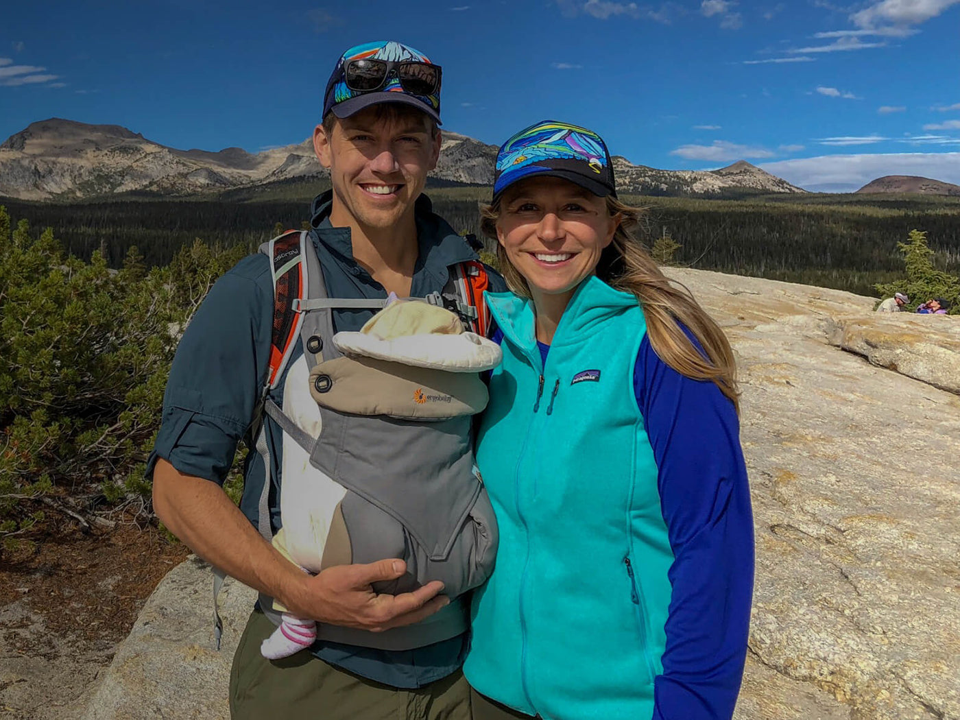 Two parents wearing Sunday Afternoons Artist Series Truckers, smiling for a photo while out on a hike