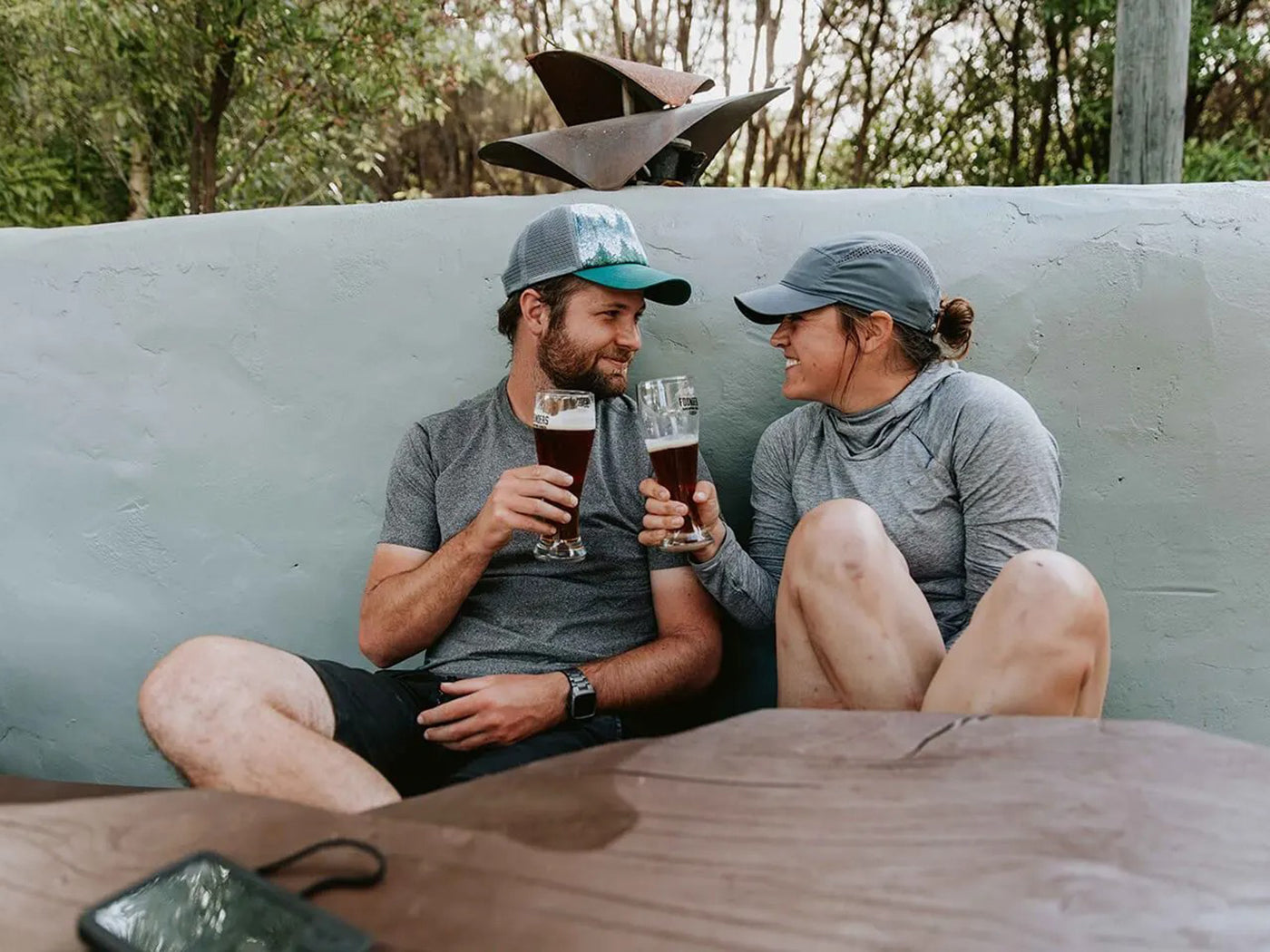 A couple having a pint of beer at Awaroa Lodge, a hotel accessible only by foot, boat or helicopter, inside Abel Tasman’s National Park.