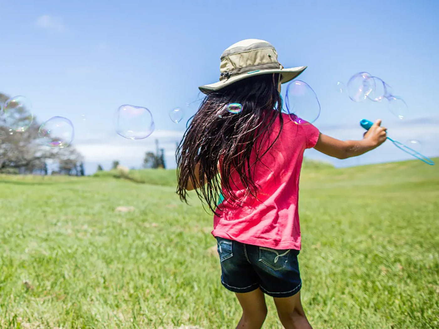 girl making bubbles wearing a Sunday Afternoons Kids' Clear Creek Boonie hat