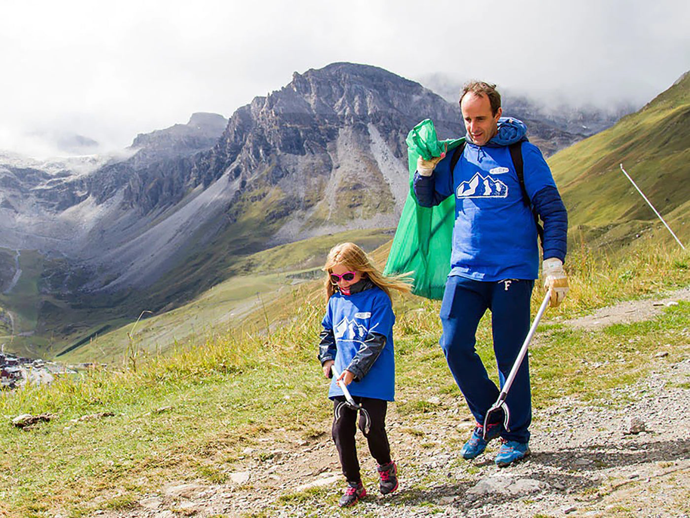 Father and daughter picking up trash on a mountain