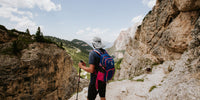 A man standing on a mountain trail, turned around, looking out over the landscape wearing a Sunday Afternoons Adventure Hat.