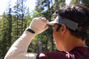 A man, turned around looking off in the distance, in nature, wearing a Sunday Afternoons visor.